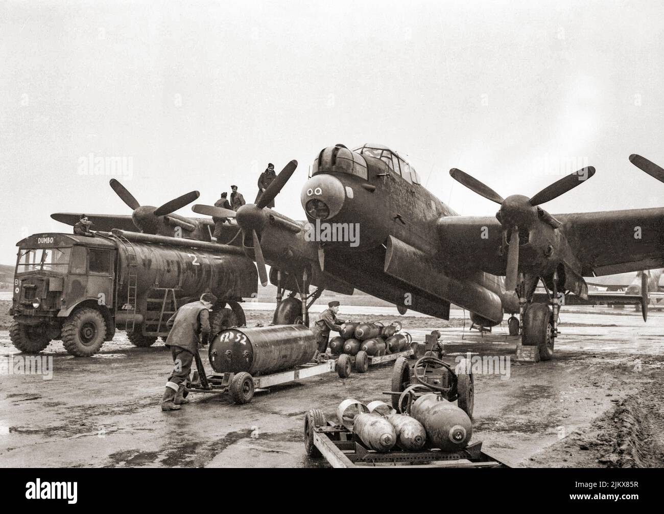 Bodentrupps tanken und bombardieren eine Avro Lancaster der Squadron RAF Nr. 75 (Neuseeland) in Mepal, Cambridgeshire, England, für einen nächtlichen Überfall auf Krefeld, Deutschland. Die Bombenladung besteht aus einem 4.000-lb HC 'Cookie' und gemischten 1.000-lb und 500-lb MC-Bomben. Die 'Lancs' wurden erstmals 1942 beim RAF Bomber Command eingesetzt, und als die strategische Bombenoffensive über Europa an Fahrt gewann, wurde sie zum Hauptflugzeug für die folgenden nächtlichen Bombenkampagnen. Stockfoto