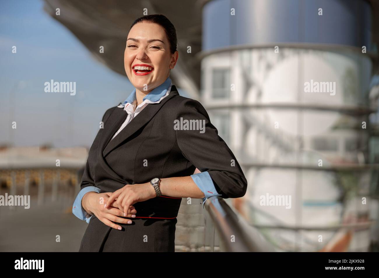 Hübsche weibliche Flugbegleiterin, die in der Nähe des Terminals stand und lachte Stockfoto