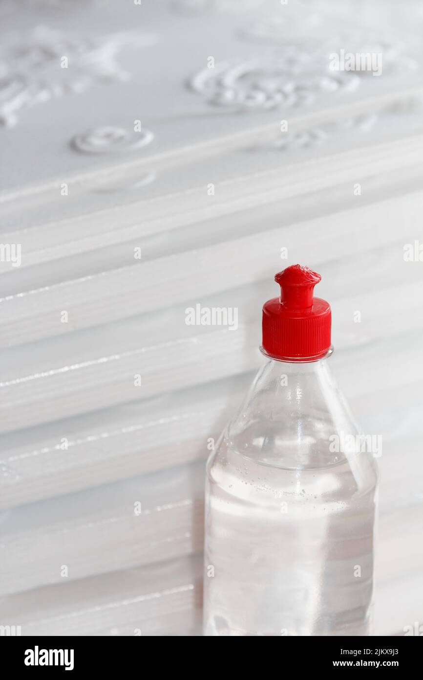 Flasche mit Acryl, vielseitiger, transparenter Klebstoff für Reparaturarbeiten, steht vor dem Hintergrund von gepressten Schaumplatten für die Decke Stockfoto