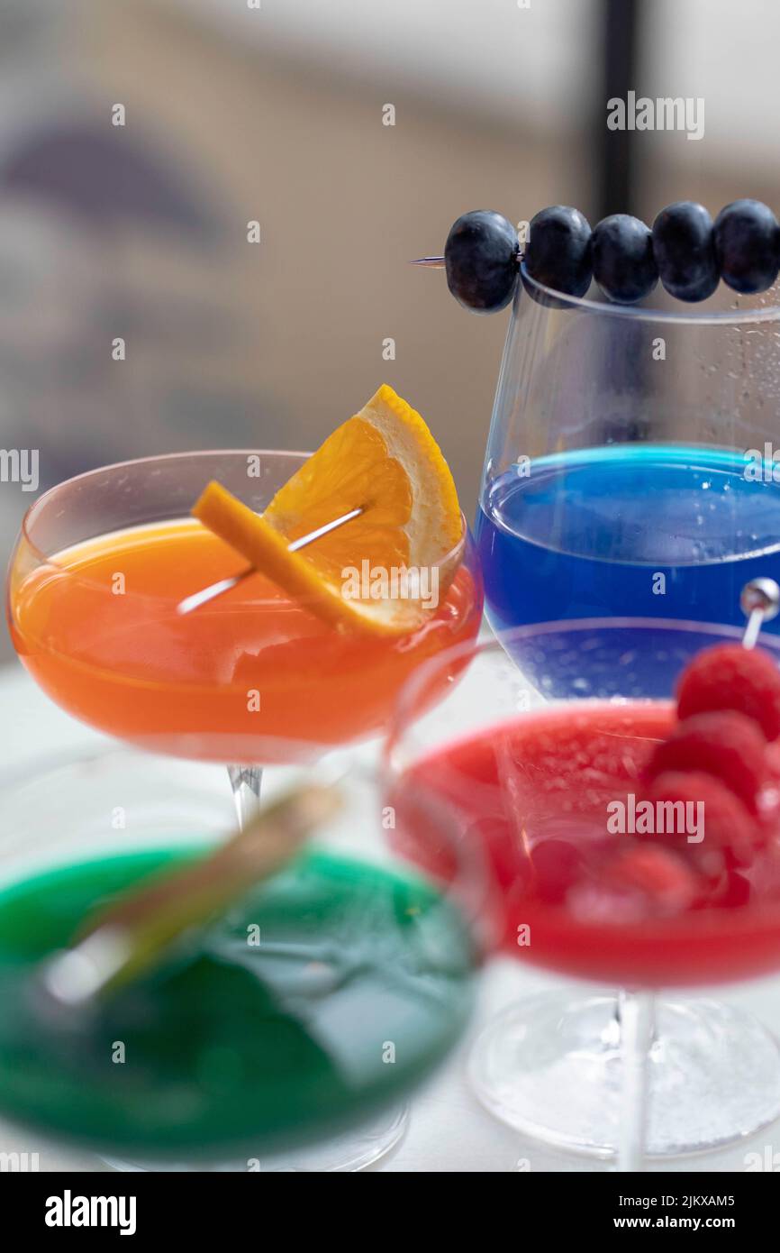 Eine vertikale Aufnahme von bunten Cocktails in Gläsern, die mit Früchten und Beeren dekoriert sind Stockfoto