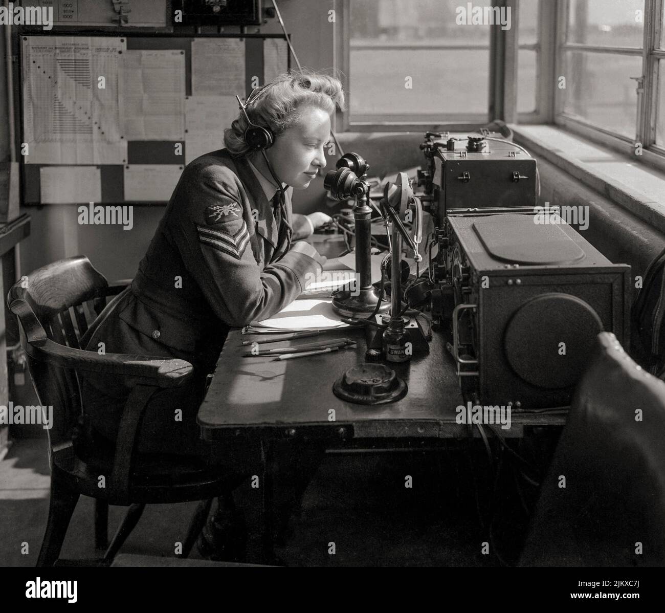Ein WAAF-Funktelefonbetreiber, der vom Wachbüro einer Bomber Command Station aus mit dem Flugzeug kommuniziert. Die WAAF wurde 1939 gegründet, als die Regierung beschloss, dass ein separater Frauenflugdienst notwendig war. Die WAAF war weder eine unabhängige Organisation noch war sie vollständig in die RAF integriert. Vielmehr war sie mit der RAF verknüpft, so dass, wann immer möglich, das RAF-Personal durch Frauen ersetzt werden konnte. Stockfoto
