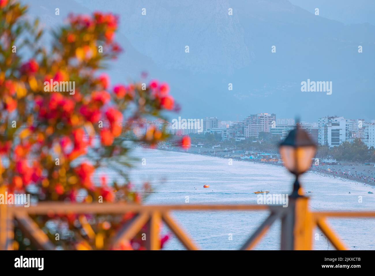 Berühmter Strand von Konyaalti, landschaftlich reizvoller Blick auf die Stadt von einem Aussichtspunkt aus. Dekorative Laterne und Holzzaun und blühende Blumen im Frühling. Reisedesti Stockfoto
