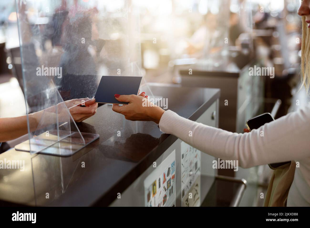 Eine weibliche Fluggast übergibt den Reisepass am Check-in-Schalter am Flughafen Stockfoto