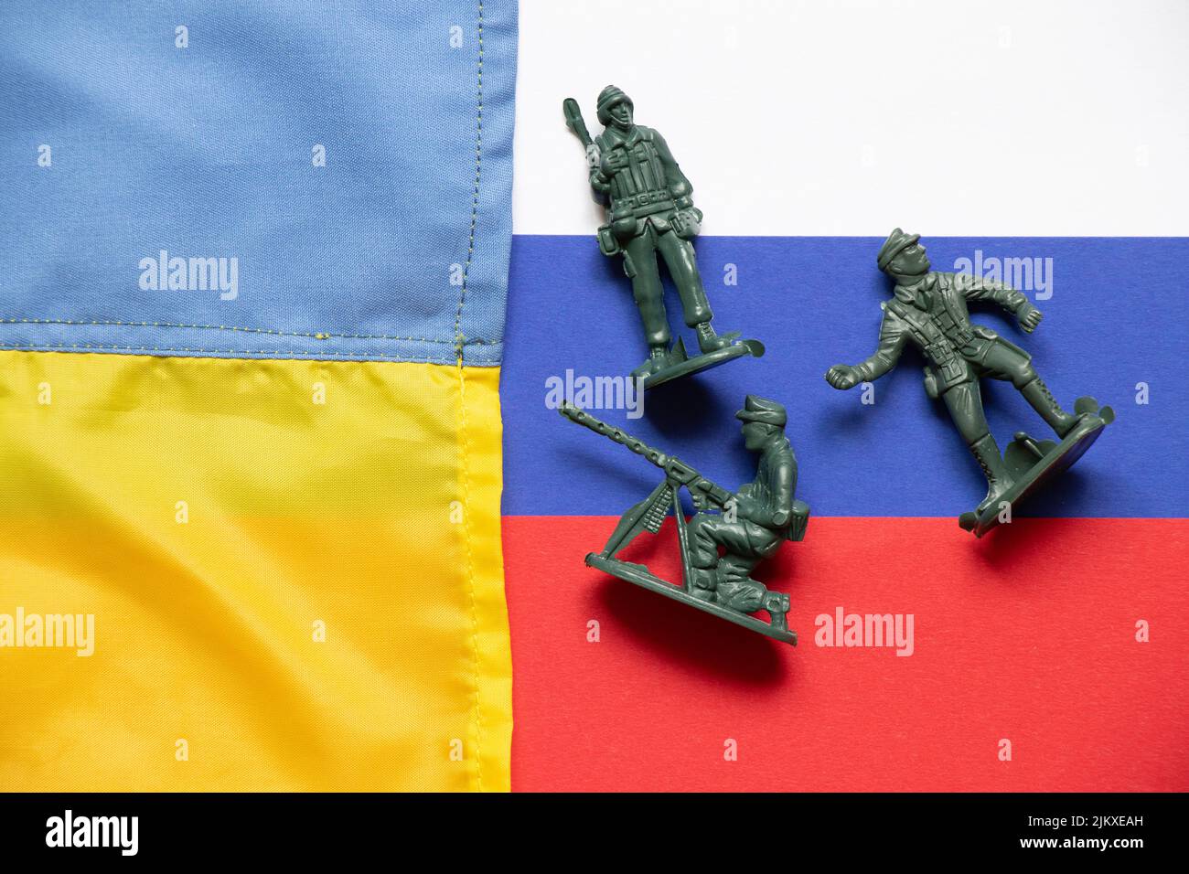 Die Flagge der Ukraine und Russland und auf den russischen Flaggen sind verstreute Plastiksoldaten für Kinder, der ukrainisch-russische Krieg Stockfoto
