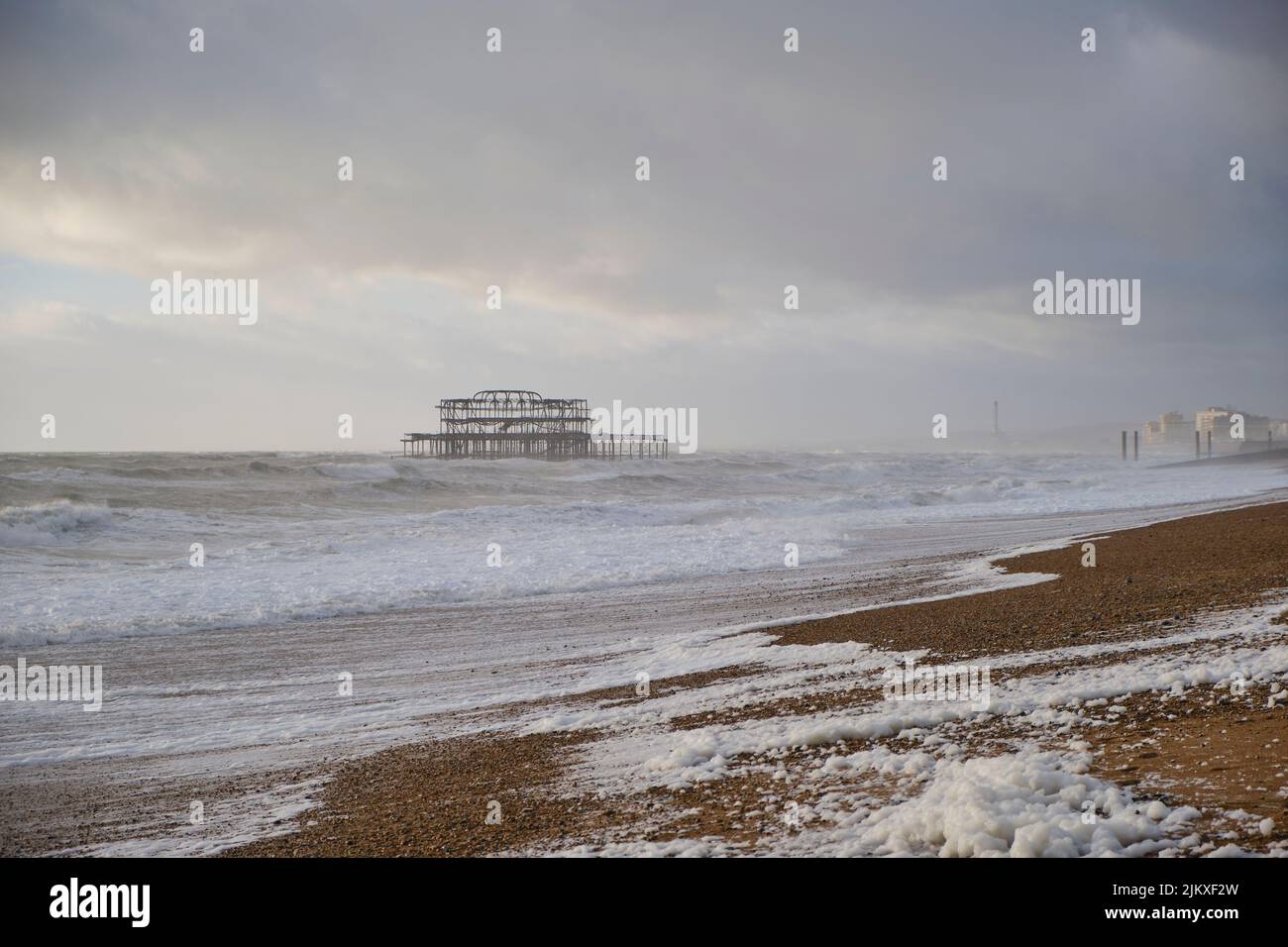 Eine Küste von Brighton, bedeckt mit schmelzendem Schnee, und ein alter Pier an einem bewölkten Tag, das Vereinigte Königreich Stockfoto