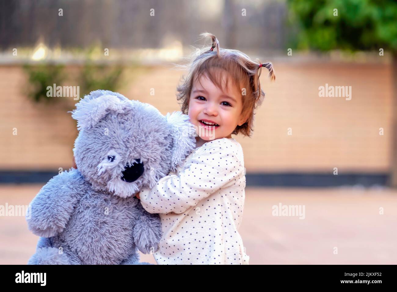 Lächelndes Mädchen umarmte ihren Teddy Stockfoto