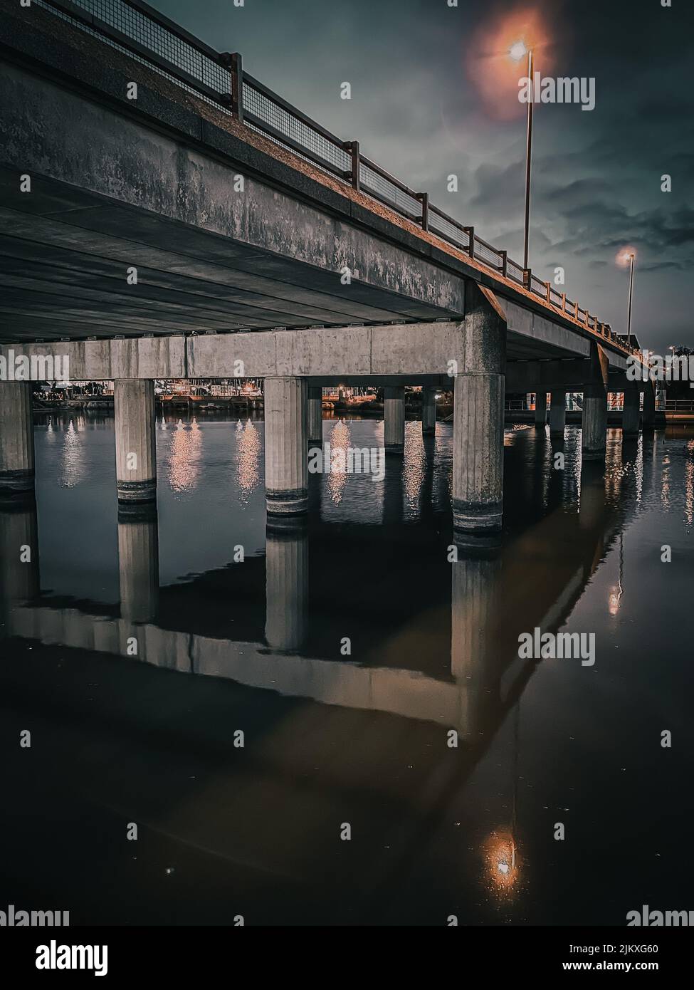 Eine vertikale Aufnahme einer Brücke mit ihrer Spiegelung auf dem Wasser unter ihr am Abend Stockfoto