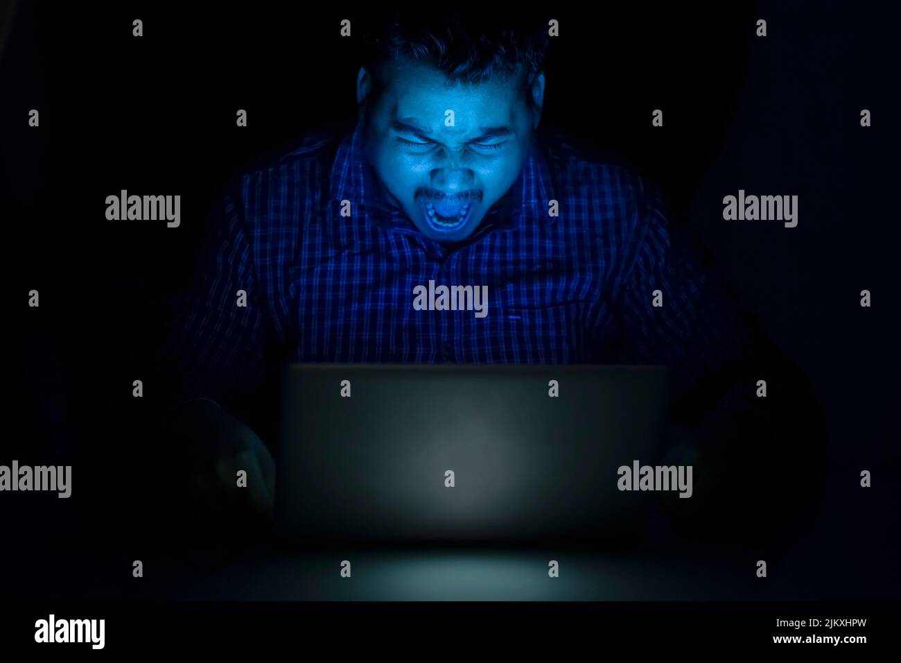 Hacker brüllen oder brüllen nachts gegen den Laptop-Bildschirm Stockfoto
