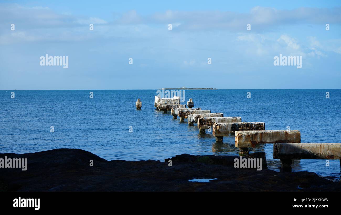 Ein schöner Blick auf das ruhige blaue Meer mit alten Steinwellen-Breakern Stockfoto