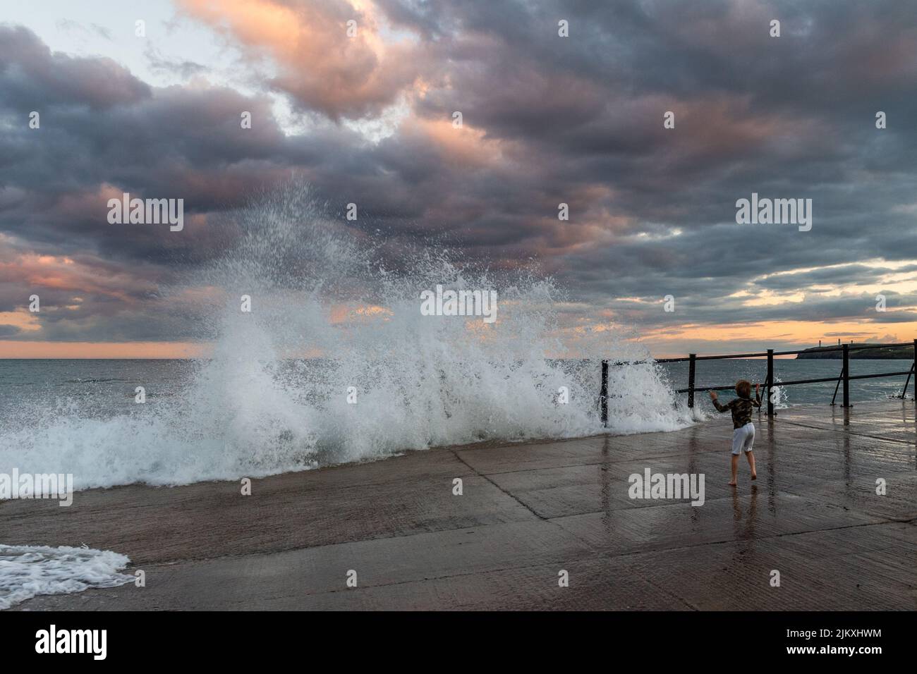 Tramore, County Waterford, Irland. 3. August 2022. Die Menschen beobachten die großen Wellen vom Slipway in Tramore, wenn die Sonne nach einem Tag voller Sonnenschein und warmen Temperaturen untergeht. Quelle: AG News/Alamy Live News Stockfoto