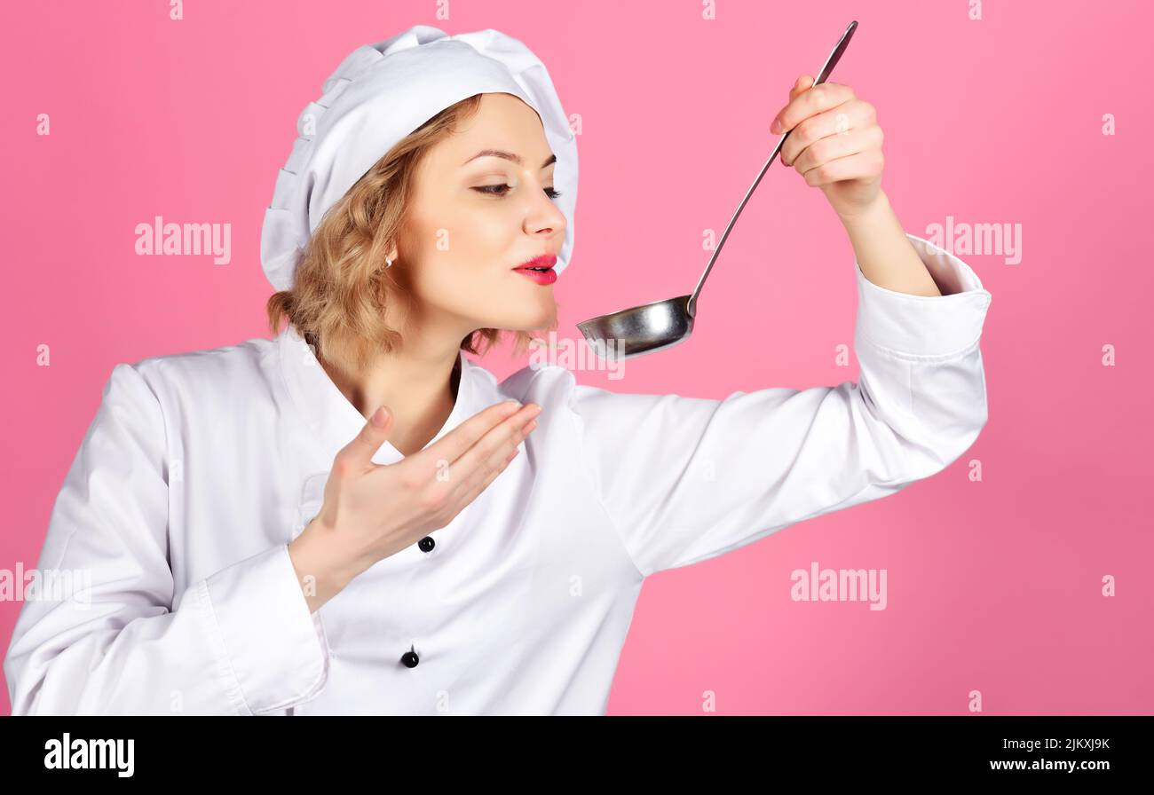 Weibliche Köchin in weißer Uniform, die Essen mit Löffel schmeckte. Kochen und professionelle kulinarische. Stockfoto