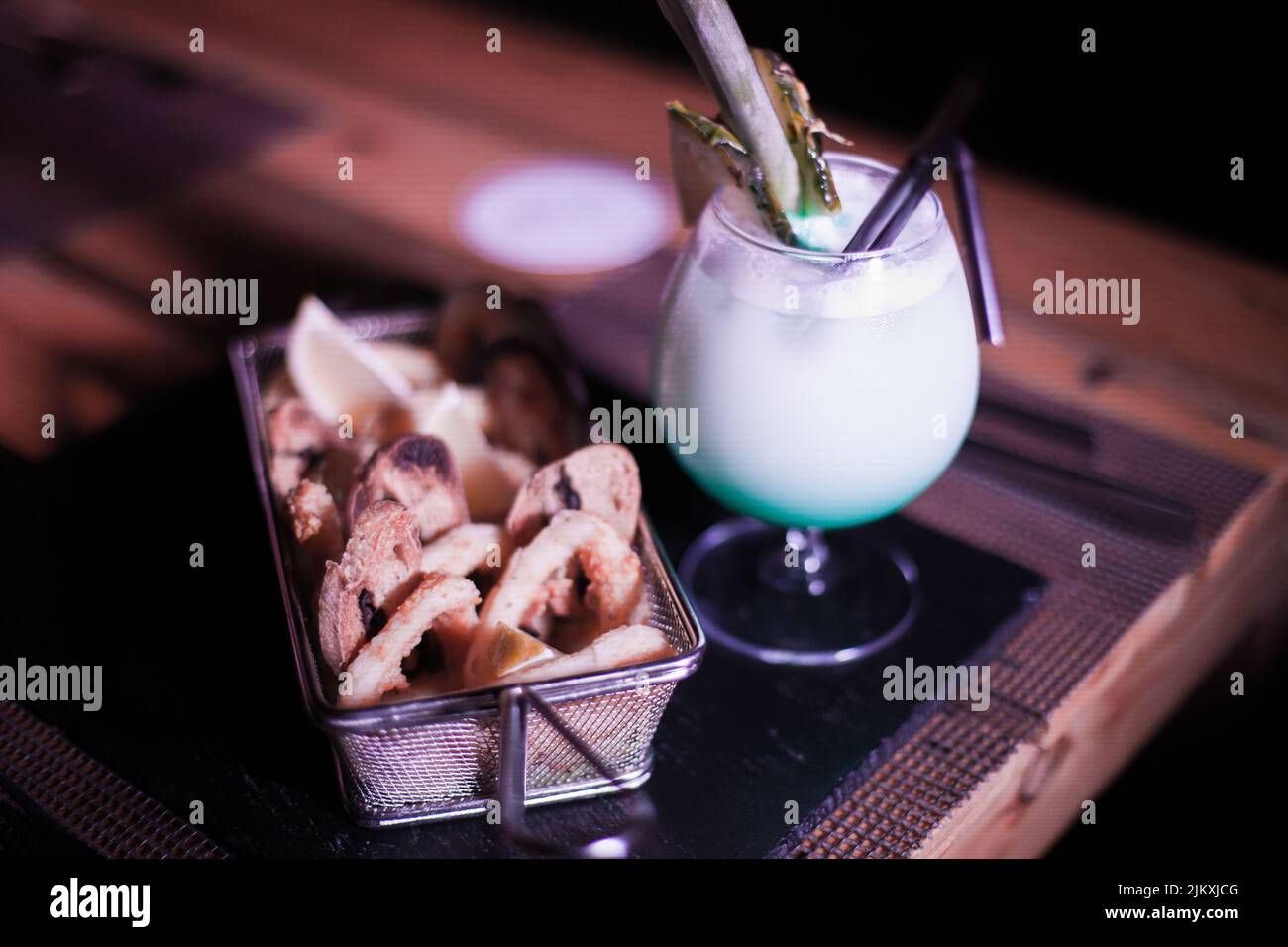 Kleine Portion Zwiebelringe mit einem kalten Cocktailgetränk daneben Stockfoto