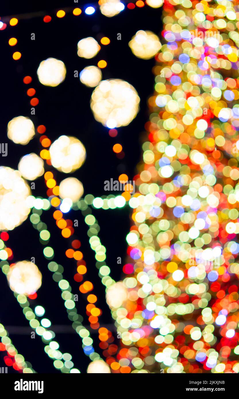Großer Weihnachtsbaum zu Neujahr, geschmückt mit leuchtenden bunten Girlanden und Beleuchtung in der Nacht. Weihnachtsbaum mit blinkenden Lichtern. Unscharfer Hintergrund. Neujahr und Weihnachtsferien Stockfoto