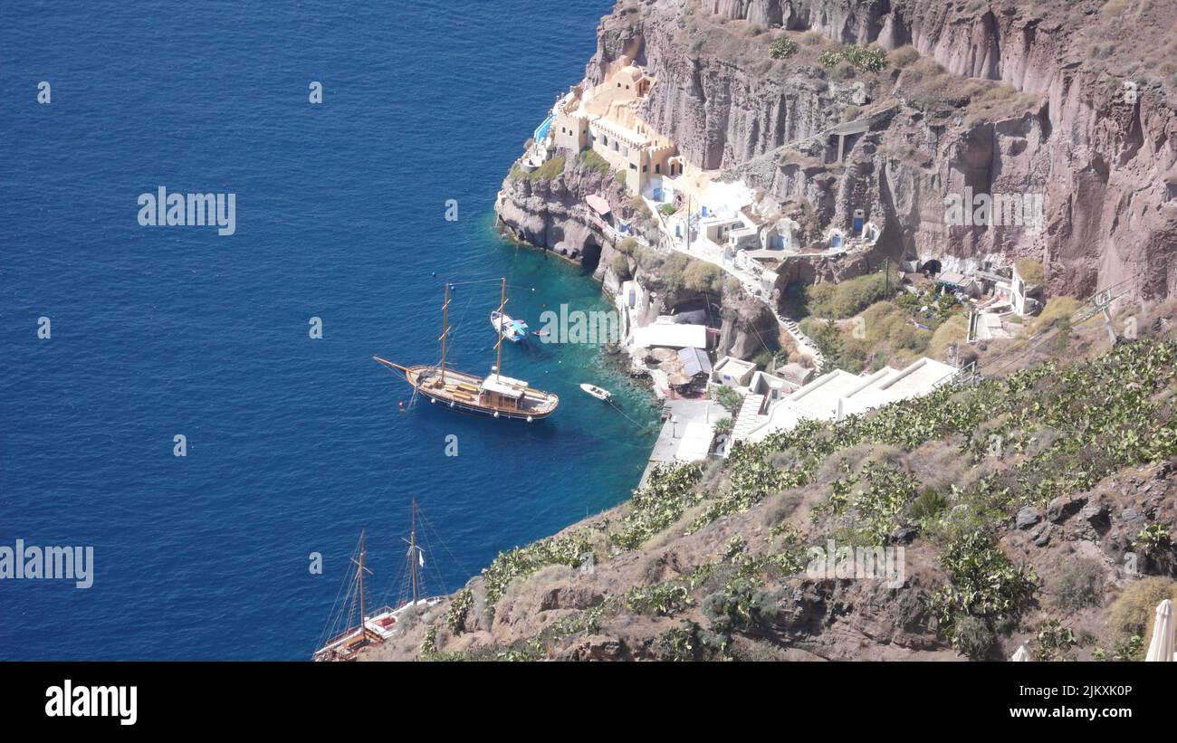 Eine Luftaufnahme von Klippen in der Nähe der ägäischen Küste und einem Schiff an der Küste von Santorini, Griechenland Stockfoto