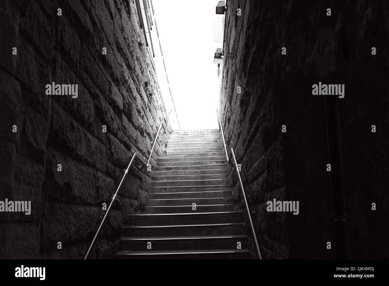 Die Treppe ist von Steinmauern umgeben, die zu einem geheimnisvollen hellen Licht an der Spitze führen Stockfoto