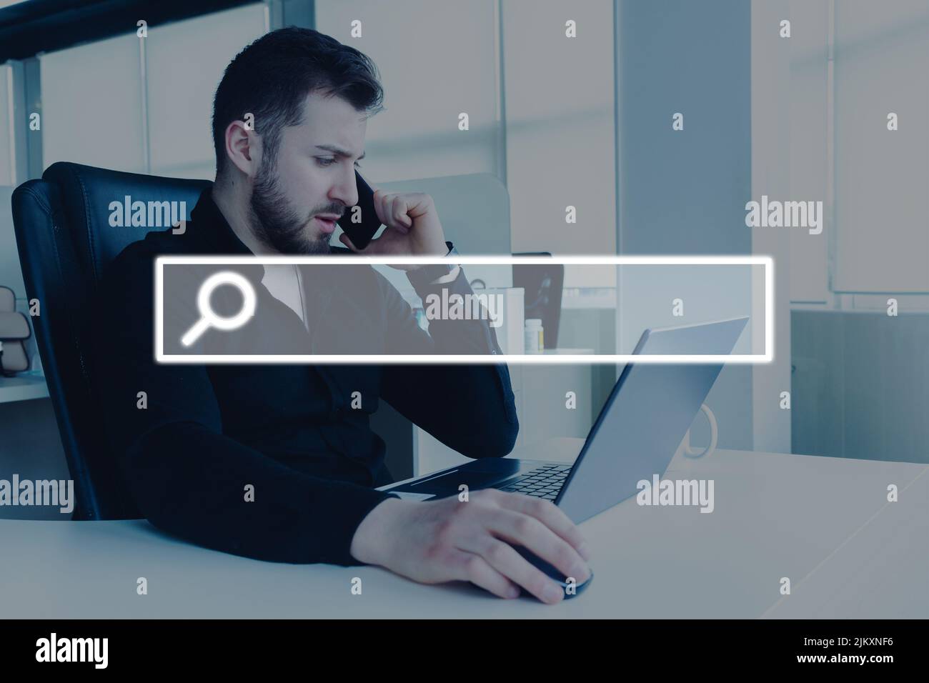 Ein junger Mann, der im Büro an einem Laptop mit einer Suchschaltfläche auf dem Bildschirm arbeitet Stockfoto