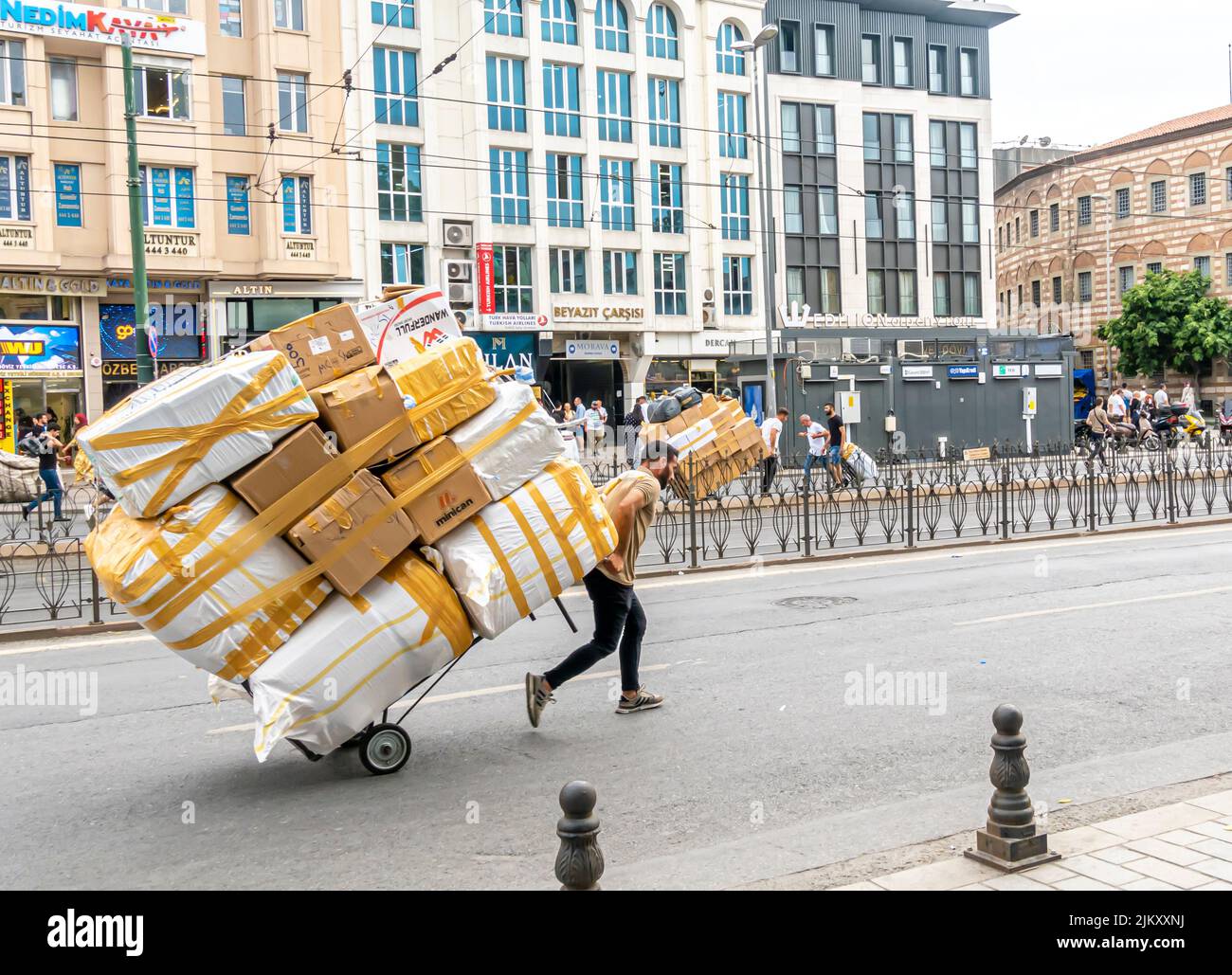 Ein Jugendlicher, der einen großen, von Hand gezogenen Wagen mit eingewickelten Schachteln schleppt. Fatih, Istanbul, Türkei Stockfoto