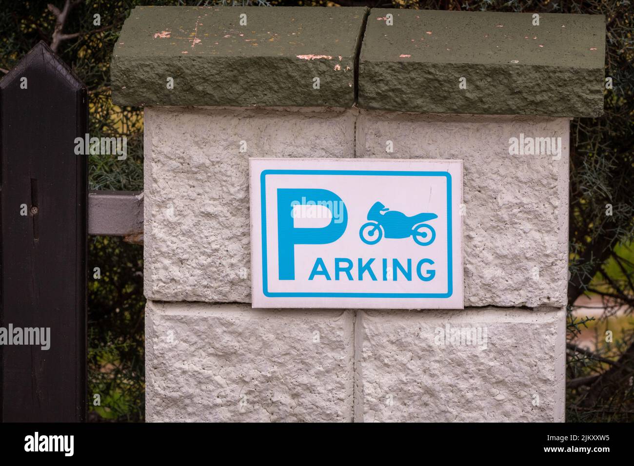 Ein Motorrad-Parkschild an einer Steinmauer Stockfoto