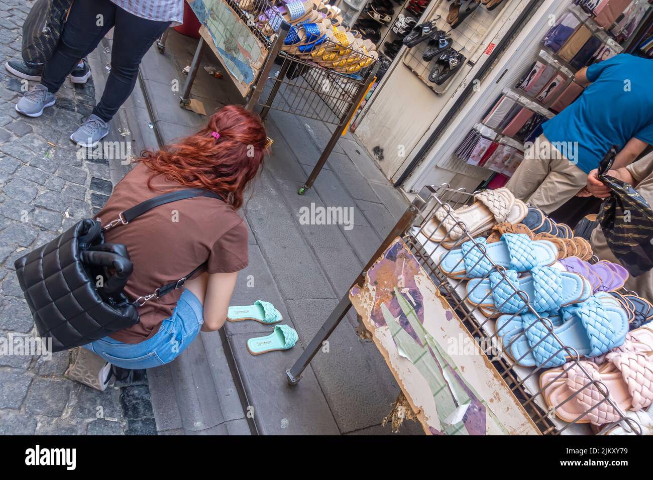 Eine Frau probiert Hausschuhe, Flip-Flops und Schuhe, die im Grand Bazaar in Istanbul, Türkei, verkauft werden Stockfoto