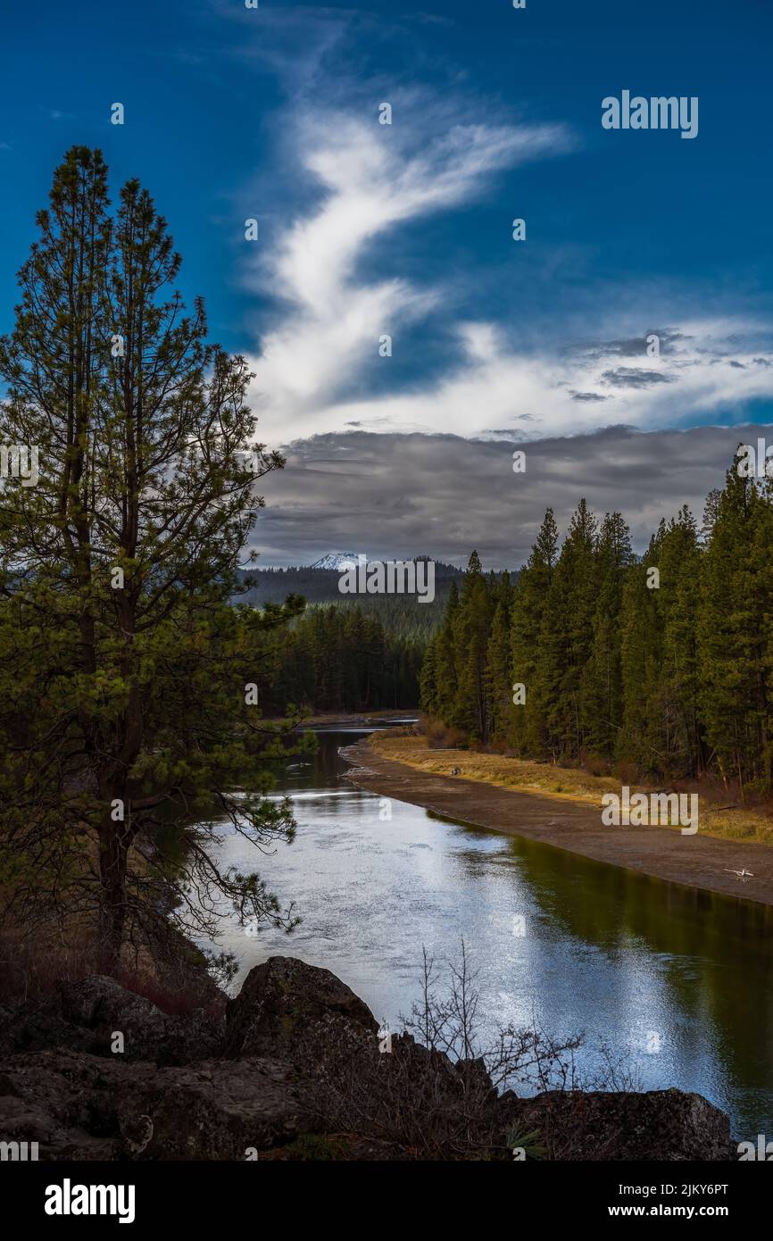 DER UNTERE DESCHUTES-FLUSS, GESÄUMT VON BÄUMEN UND EINER WUNDERSCHÖNEN SPIEGELUNG IM FLUSS, SOWIE EIN WOLKIGER HIMMEL UND EINE MOUNT HOOD IN DER NÄHE VON SUNRIVER OREGON Stockfoto