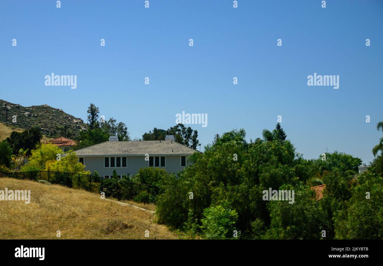 Ein ländliches Dorfgebiet mit einem Haus umgeben von hohen grünen Bäumen Stockfoto