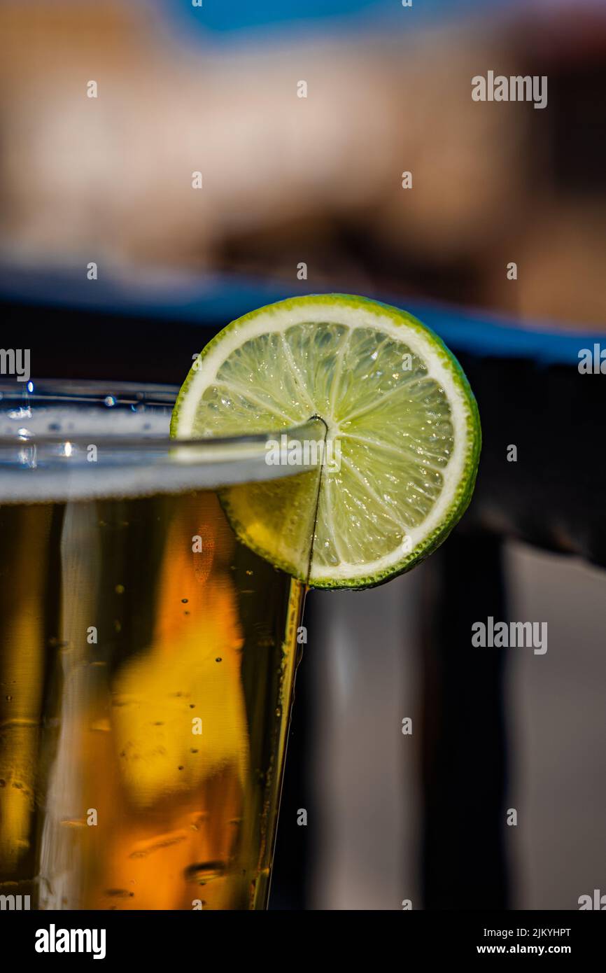 Eine vertikale Aufnahme eines Glases Bier bei heißem Wetter mit einer Scheibe Limette darin Stockfoto