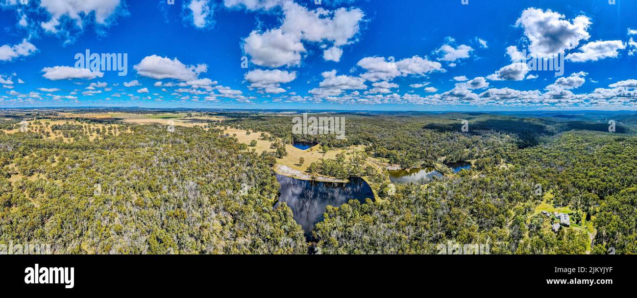 Eine Luftaufnahme der alten Mine, die jetzt ein Damm mit grünen Bäumen auf der Glen Innes Straße unter dem blau bewölkten Himmel in Australien ist Stockfoto