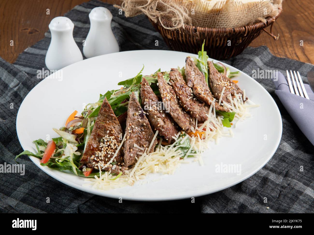 Ein leckeres Gericht, das mit Fleisch und Gemüse gekocht wird und auf einem weißen Teller auf einem Tisch serviert wird Stockfoto