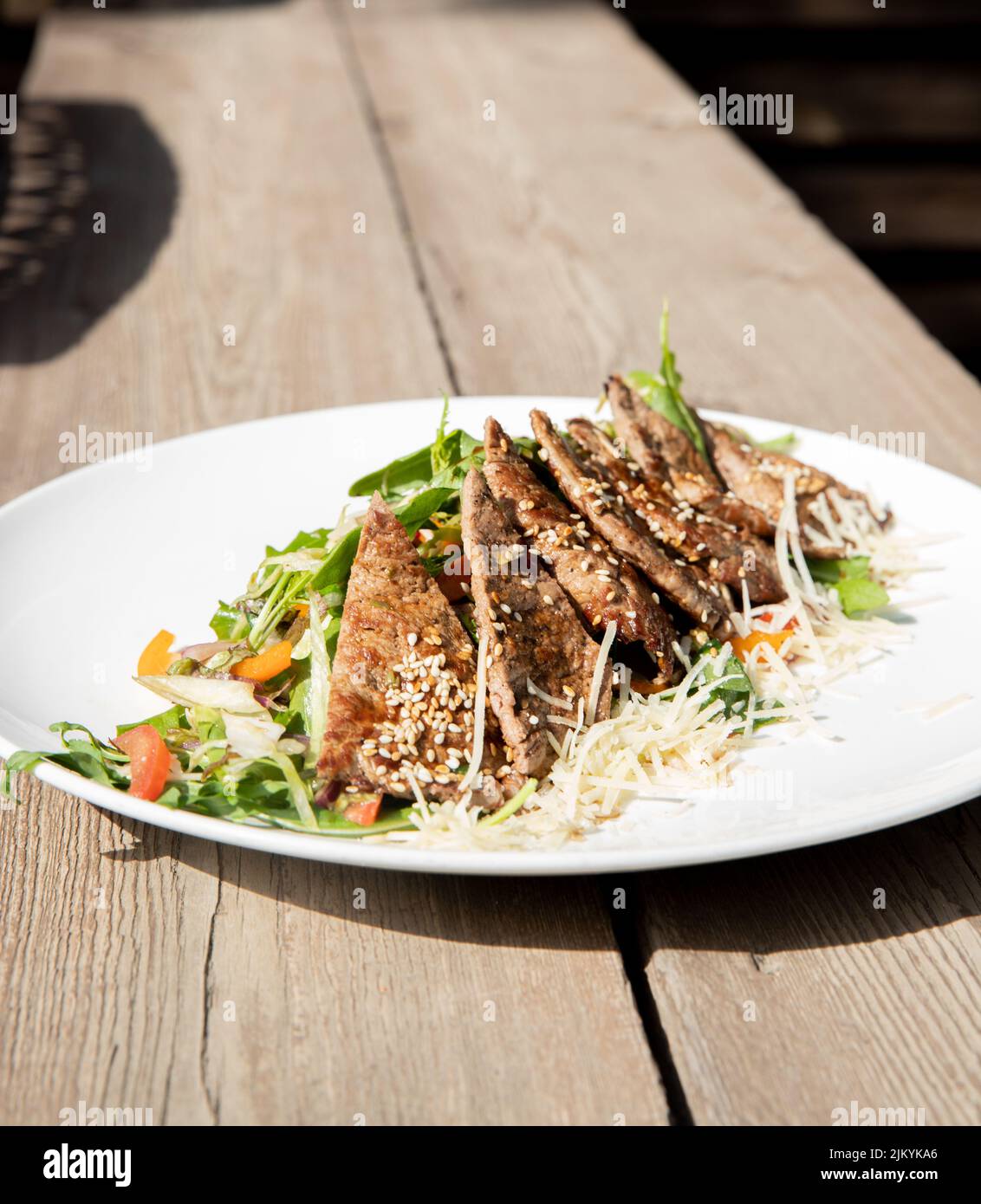 Eine vertikale Aufnahme eines leckeren Gerichts, das mit Fleisch und Gemüse auf einem weißen Teller zubereitet wird Stockfoto