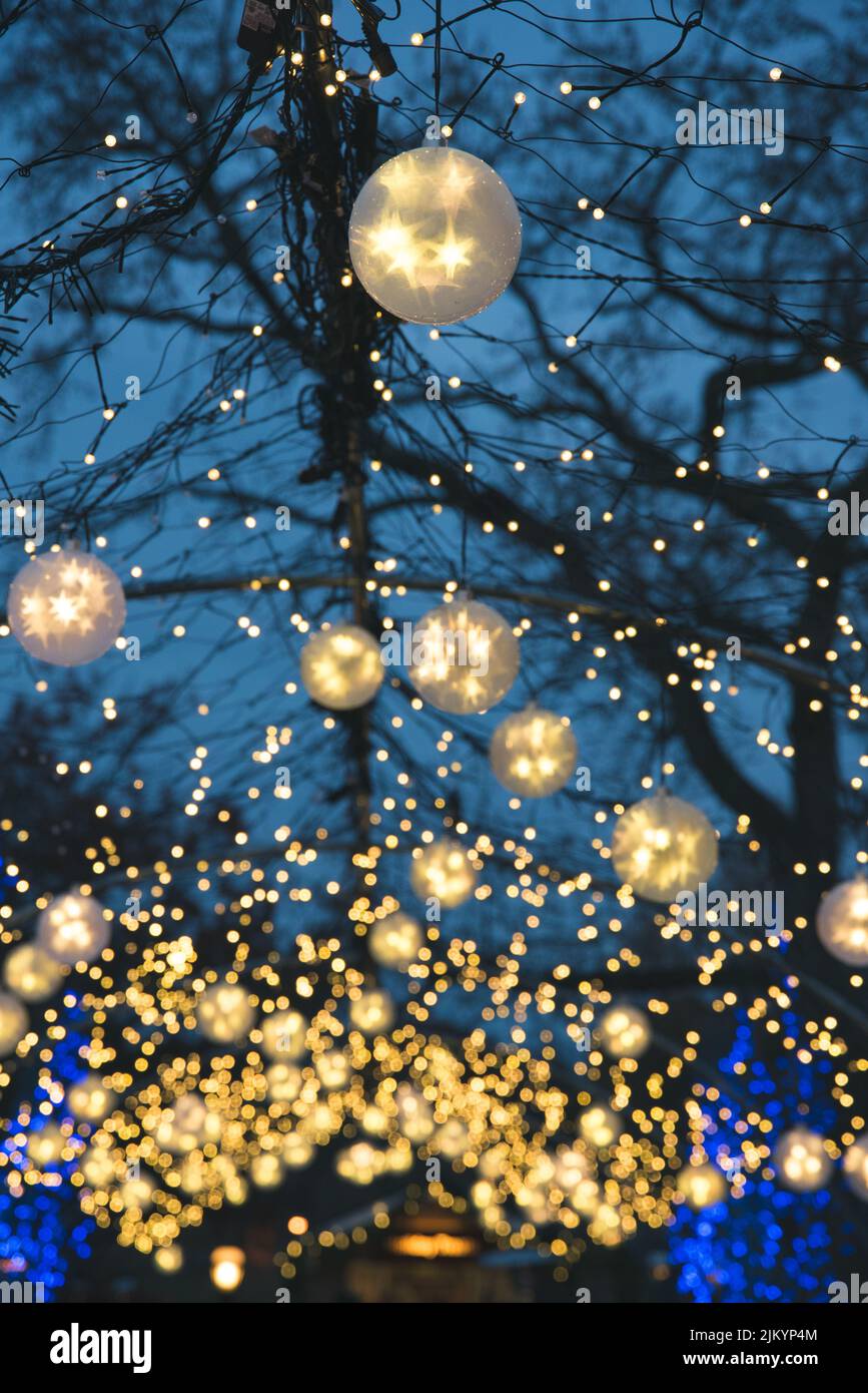 Eine vertikale Aufnahme von Winterästhetik mit Weihnachtsornamenten mit Lichtern, die an Baumzweigen hängen Stockfoto