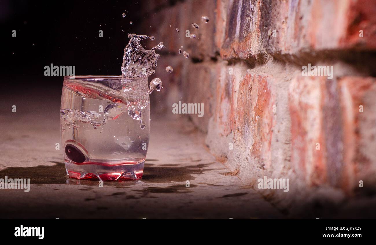 Eine Nahaufnahme von Glas, gefüllt mit Wasser in der Nähe der Ziegelwand Stockfoto