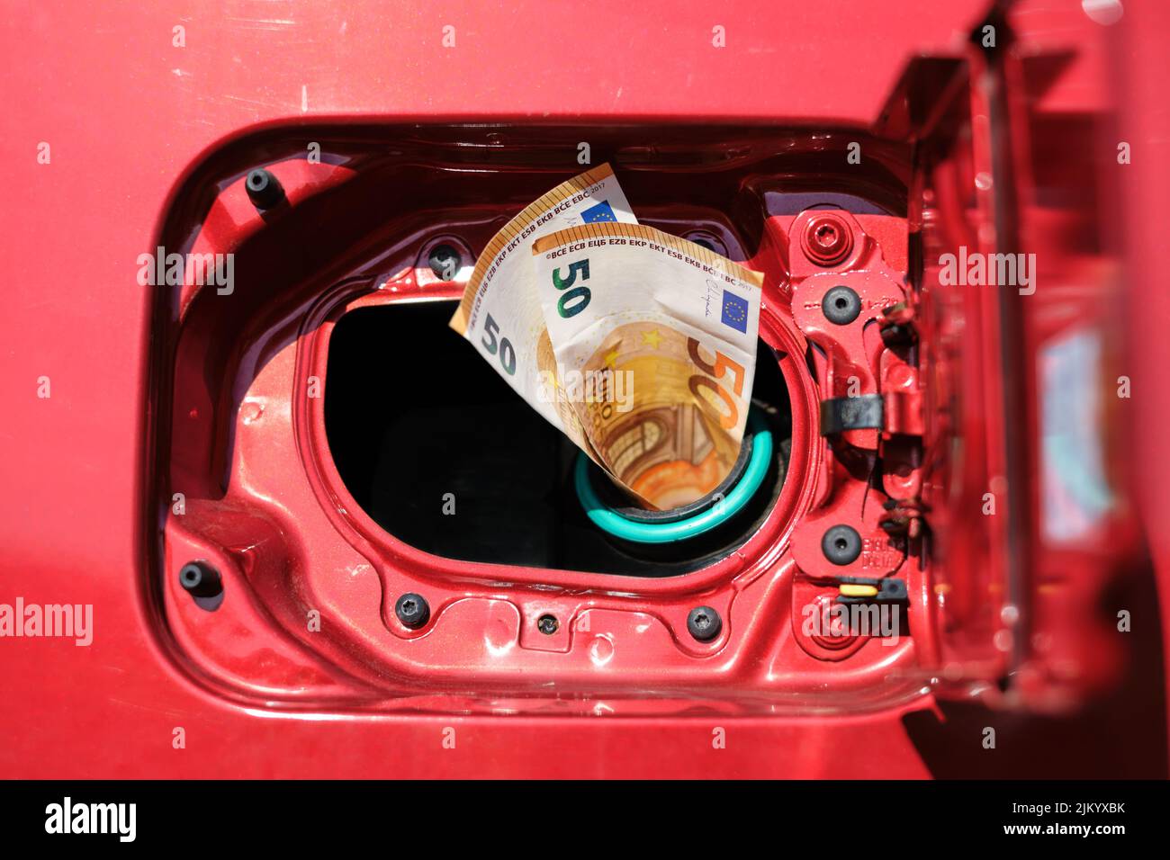 Zwei 50-Euro-Banknoten ragen aus einem Autotank, hohe Transportkosten aufgrund steigender Kraftstoffpreise. Stockfoto