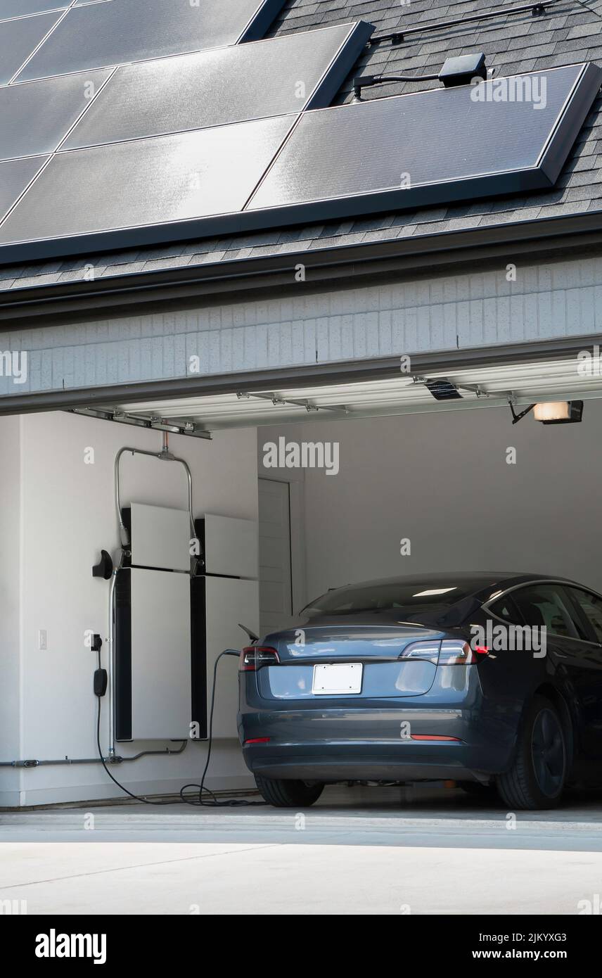 Elektrofahrzeug Charing in einer Garage mit Batterie-Backup-Generatoren, angetrieben durch Solarzellen auf einem Dach Stockfoto