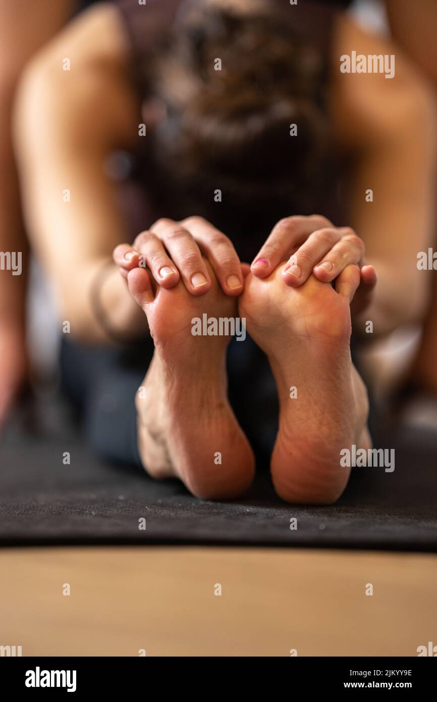 Eine vertikale Aufnahme einer Frau, die eine Yoga-Übung macht Stockfoto