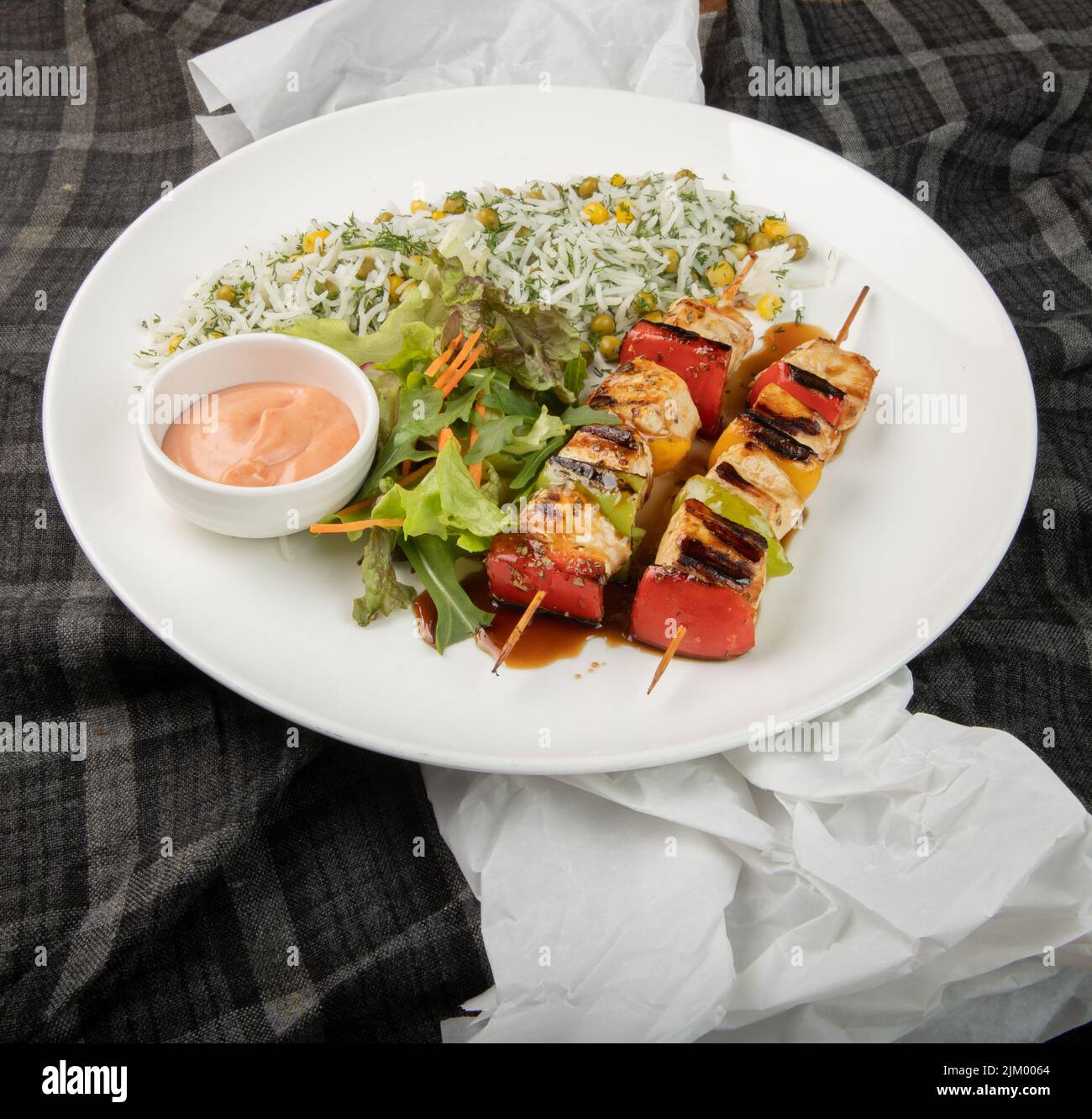 Ein Teller mit köstlichem Kebab mit frischem Gemüse auf Tischserviette und Tischtuch Stockfoto