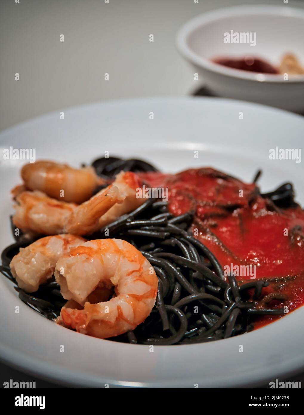 Eine vertikale Nahaufnahme einer köstlichen Garnele und Tintenfisch-Spaghetti auf einem weißen Teller Stockfoto