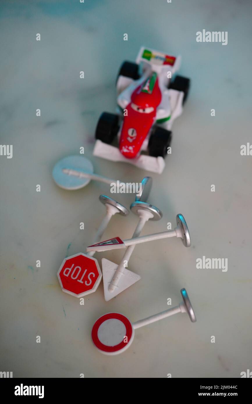 Eine vertikale Ansicht des Spielzeugmodell-Rennwagens Mattel Francesco aus dem Disney Pixar Cars Film und den Verkehrsschildern Stockfoto