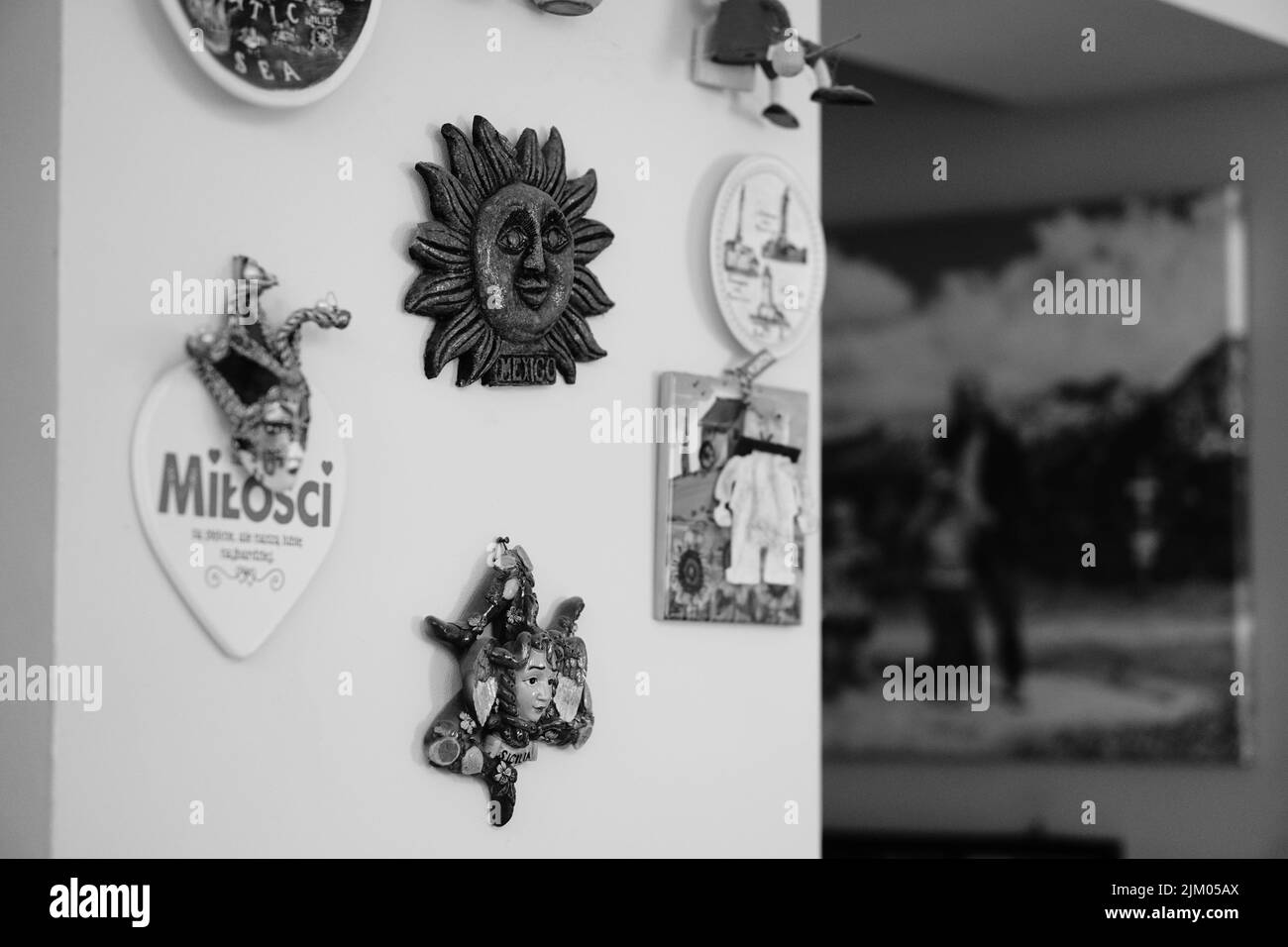 Eine Graustufe einer Gruppe verschiedener Souvenirs, die an einer Wand in einem Haus hängen Stockfoto