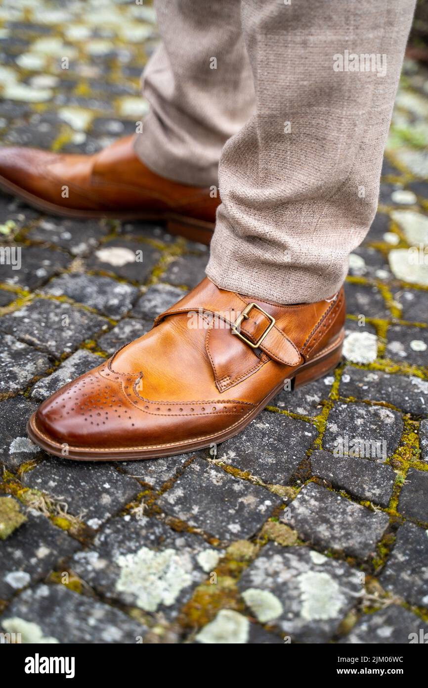 Eine vertikale Nahaufnahme von braunen Oxford-Herrenschuhen an den Füßen im Freien Stockfoto