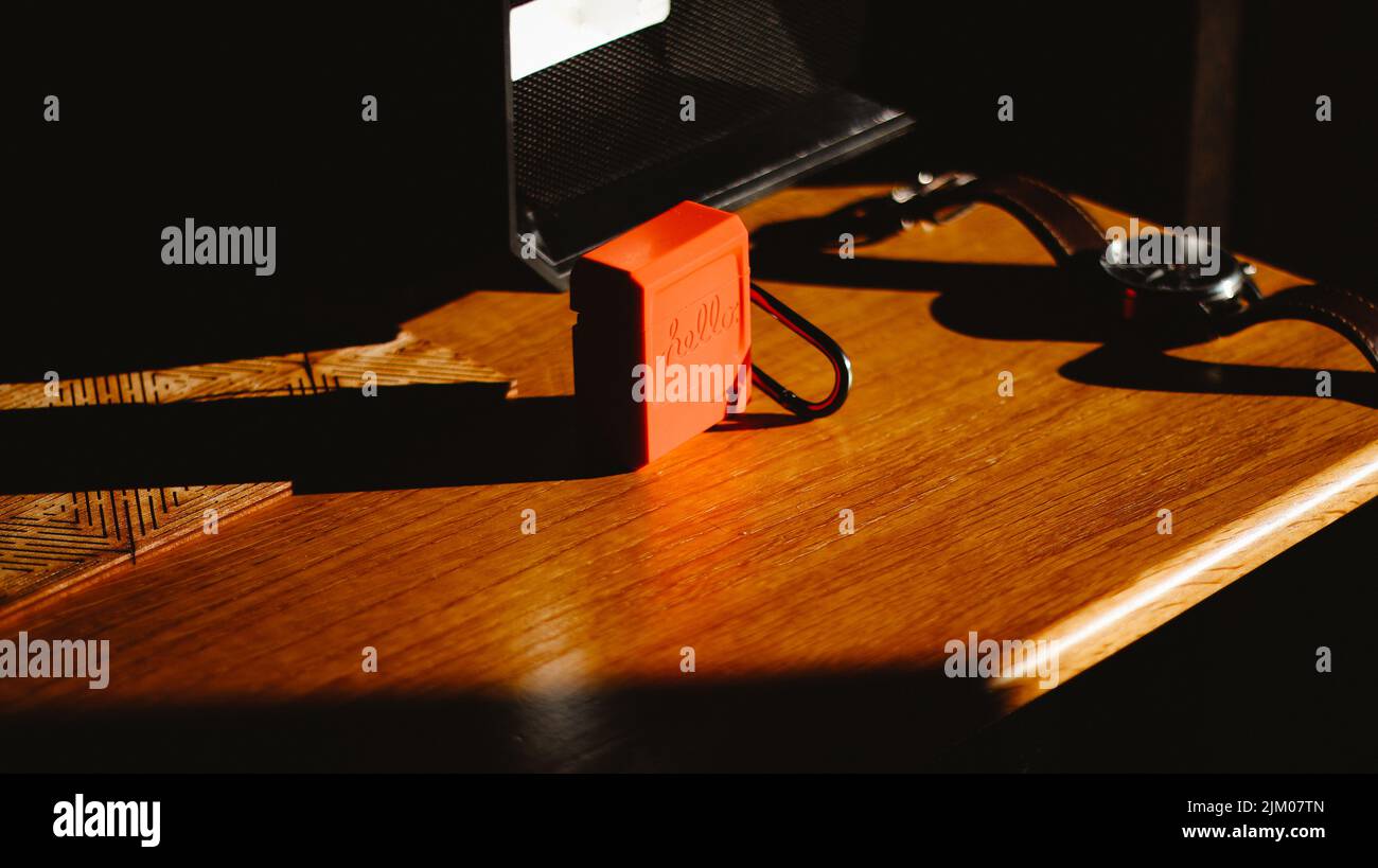 Ein orangefarbenes Kopfhörergehäuse mit einer Hello-Gravur auf einem Holztisch Stockfoto