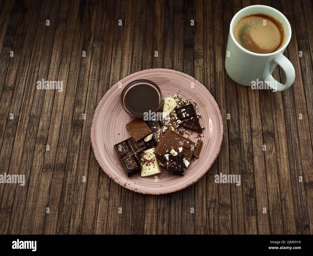 Draufsicht auf eine Auswahl an weißer, milchsauer und dunkler Schokolade, geschmolzener Schokolade und einer Tasse Kaffee Stockfoto