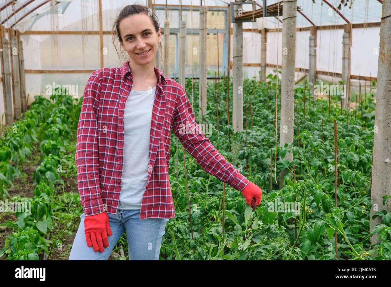 Hübsche Kindergärtnerin mit roter Arbeit Handschuhportrait im Gewächshaus Stockfoto