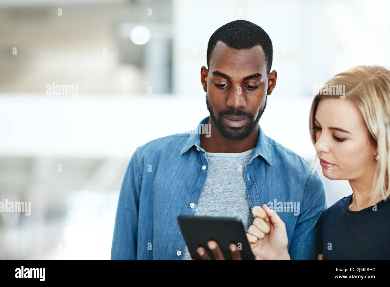Geschäftsleute sprechen zusammen, während sie Informationen, Daten oder Statistiken auf einem Tablet abrufen. Mitarbeiter, der Manager, Vorgesetzte oder Vorgesetzten um Hilfe bittet Stockfoto