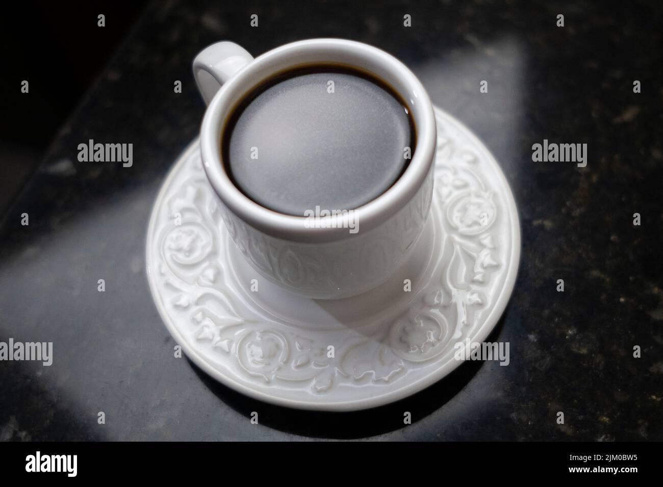 Eine Nahaufnahme einer Tasse Kaffee auf einem schwarzen Marmortisch Stockfoto