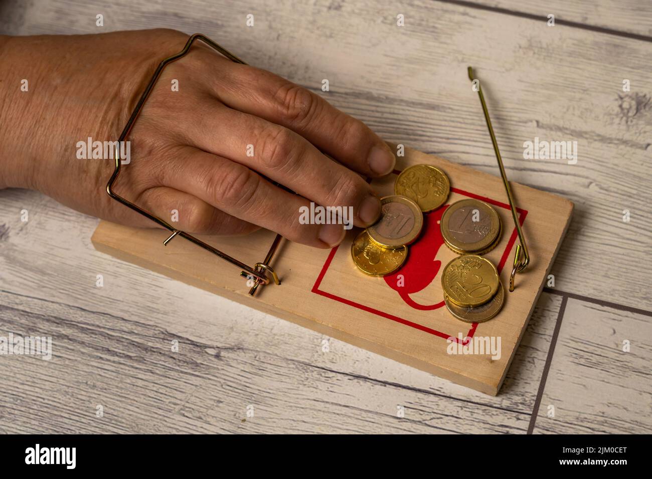 Eine Hand wird in einer Mausefalle gefangen, während sie Geld nimmt. BANKZINSEN Stockfoto