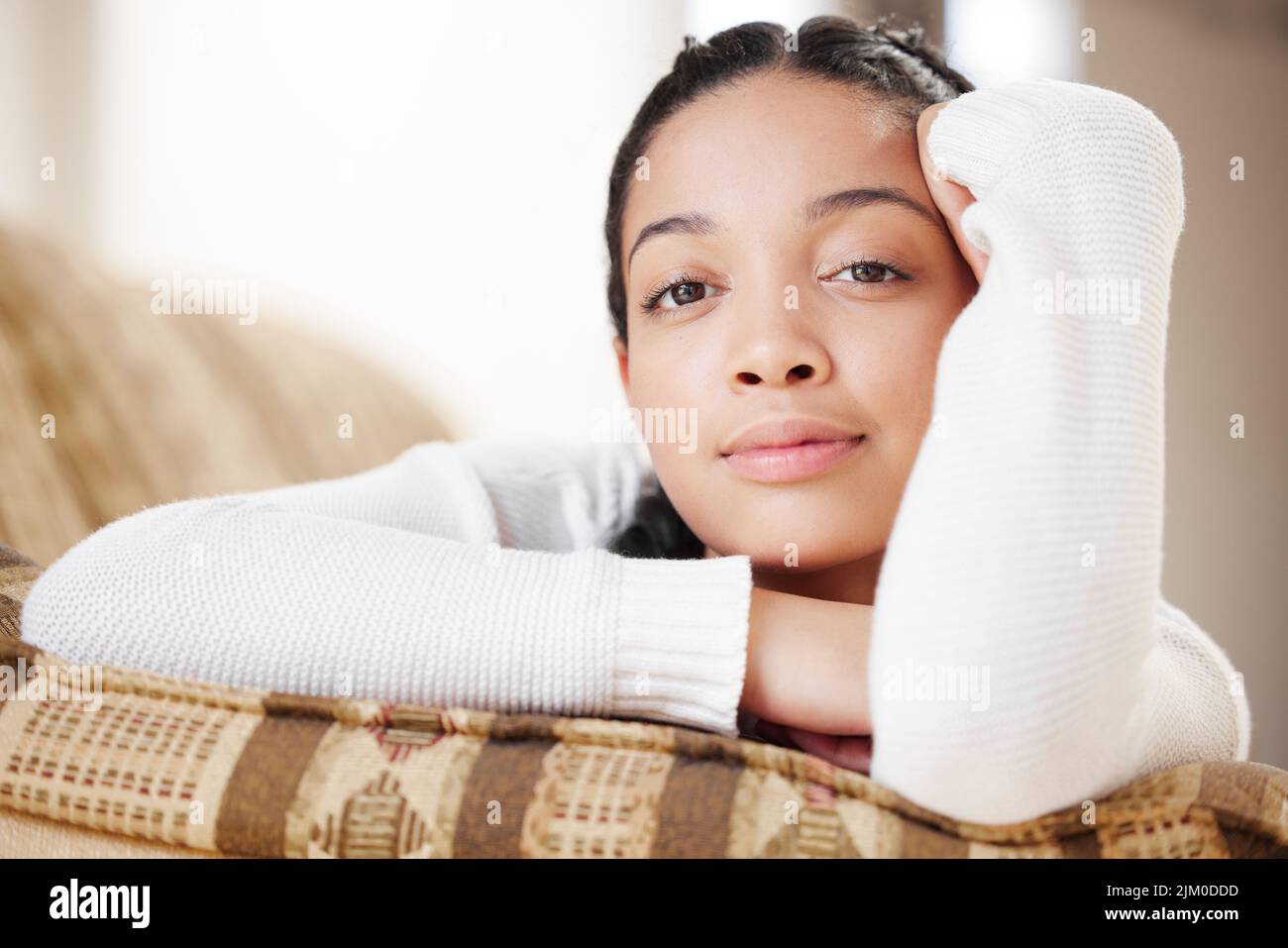 Weniger unterwegs, mehr im Fluss. Porträt einer jungen Frau, die sich zu Hause auf dem Sofa entspannt. Stockfoto