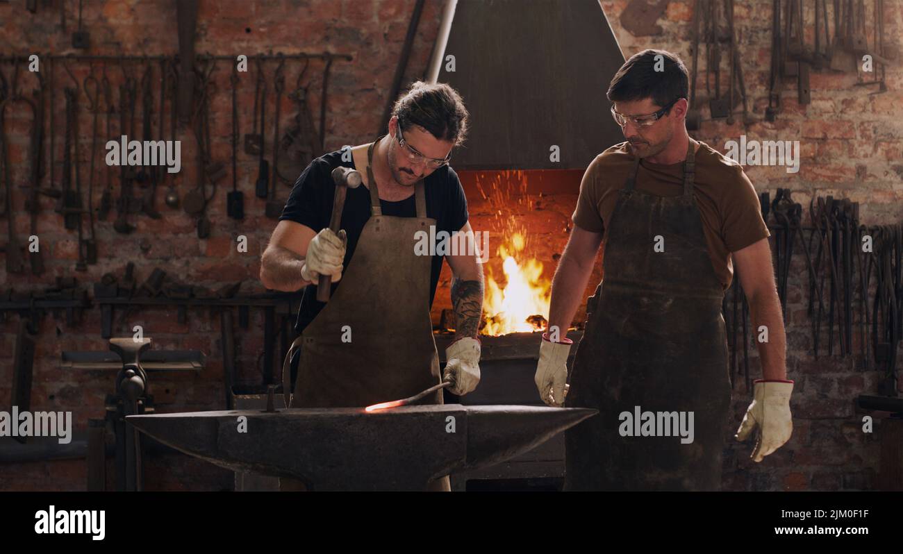 Wir verwenden Metall, um fast alles zu schaffen. Zwei Metallarbeiter arbeiten in einer Werkstatt zusammen. Stockfoto