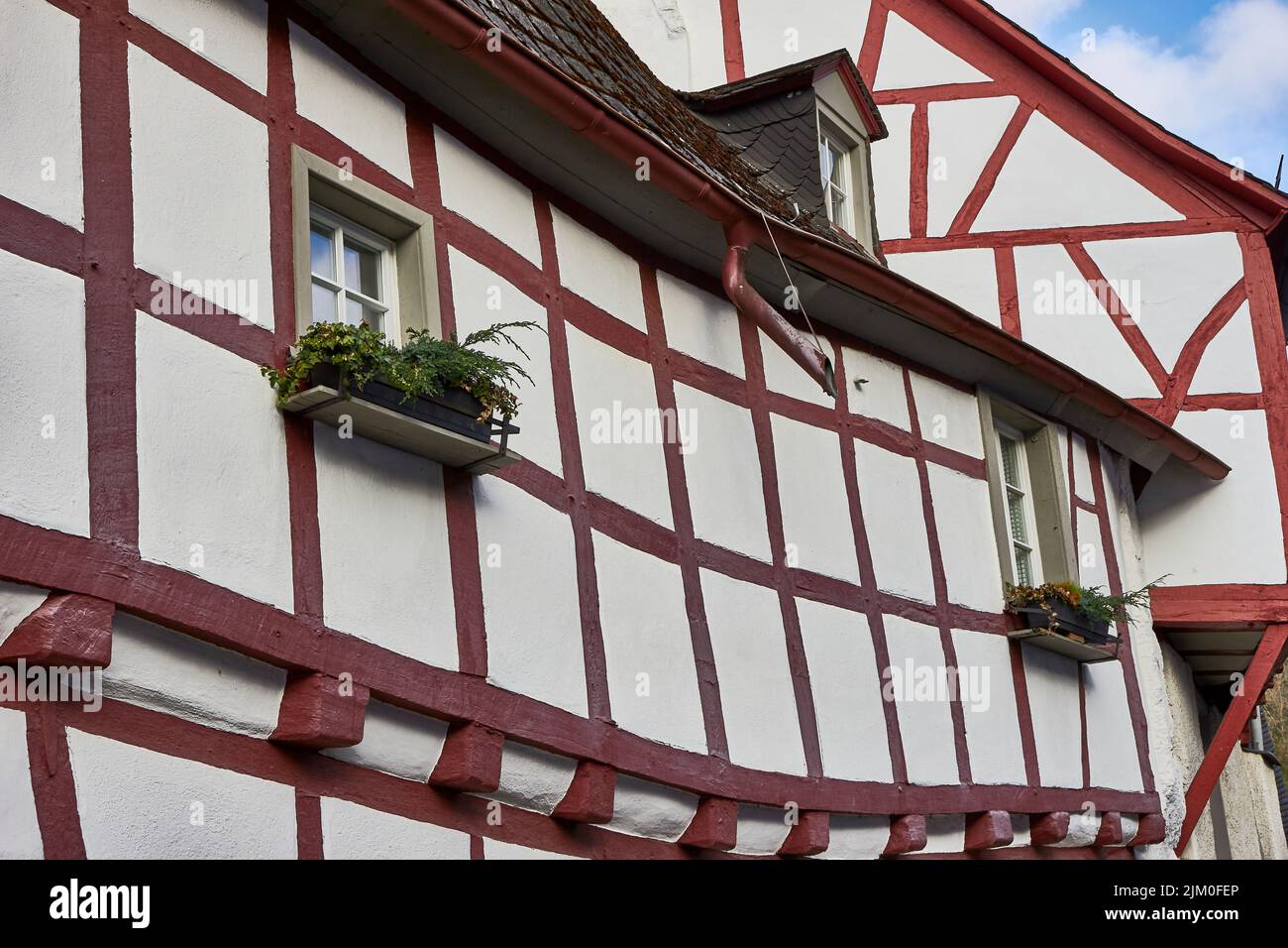 Nahaufnahme der Hausfenster mit roten Linien und Blumen in Monreal, Eifel, Deutschland Stockfoto