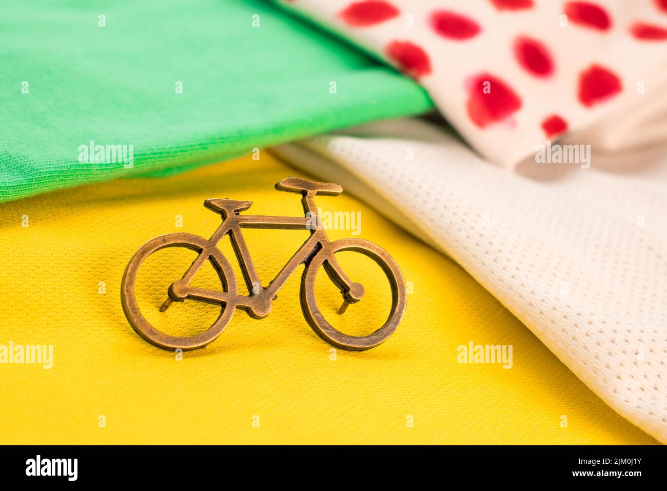 Eine kleine Fahrradnadel auf einem gelben, grünen und weißen T-Shirt für eine Tour durch Frankreich mit verschwommenem Hintergrund Stockfoto