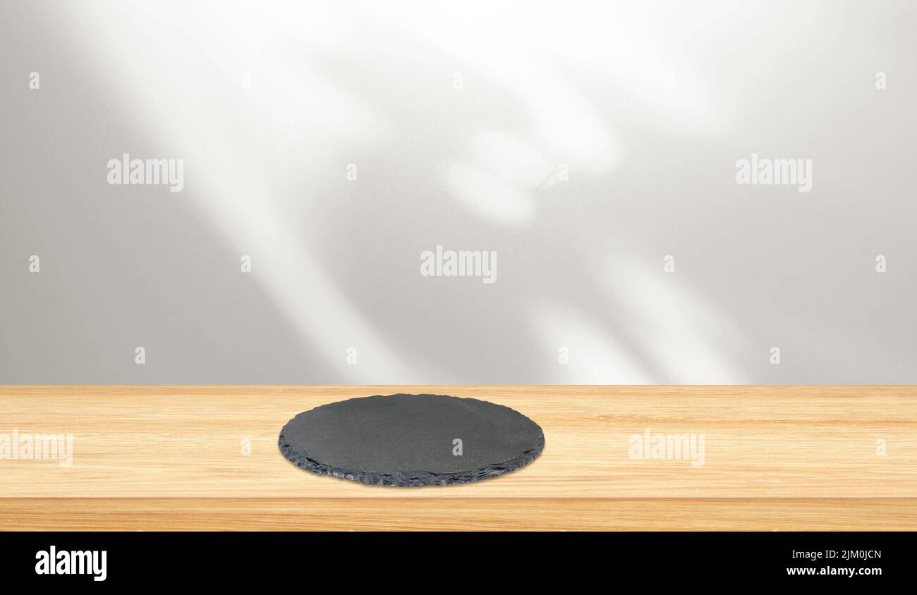 Tischplatte aus Holz und runder schwarzer Schiefer auf der Oberfläche mit Freiraum für kreative Ideen Stockfoto
